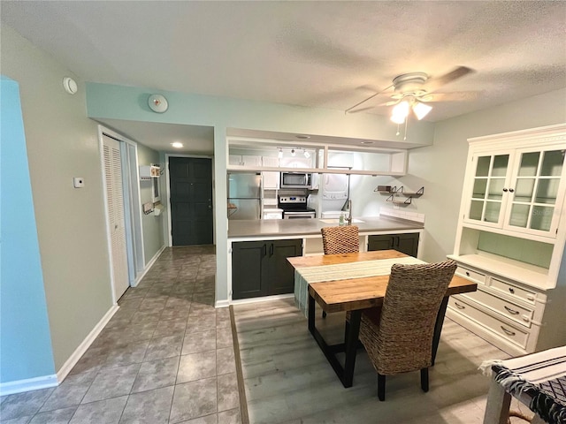 kitchen featuring light tile patterned flooring, ceiling fan, appliances with stainless steel finishes, and a textured ceiling