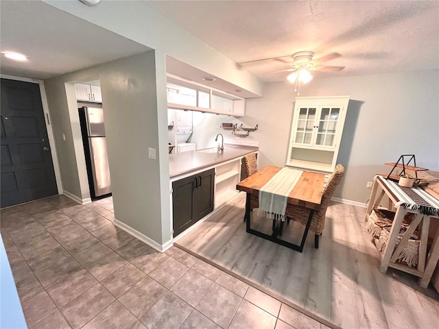 kitchen featuring ceiling fan, sink, a textured ceiling, stainless steel refrigerator, and light hardwood / wood-style floors