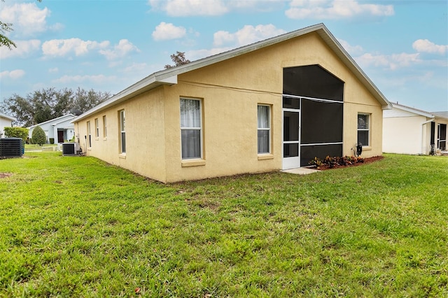 rear view of house with a lawn, a sunroom, and cooling unit