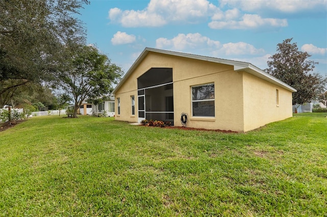 rear view of house featuring a sunroom and a yard