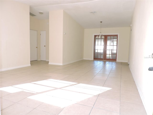 tiled spare room featuring french doors and a notable chandelier