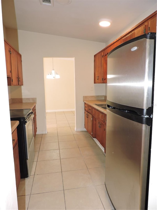 kitchen with a chandelier, pendant lighting, appliances with stainless steel finishes, and light tile patterned flooring