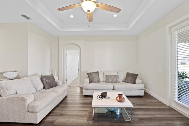 living room featuring dark hardwood / wood-style floors, a tray ceiling, crown molding, and ceiling fan