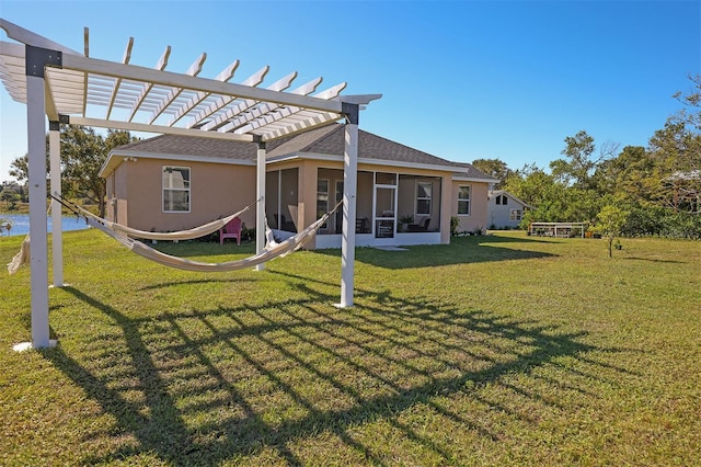 rear view of house featuring a pergola, a lawn, and a sunroom