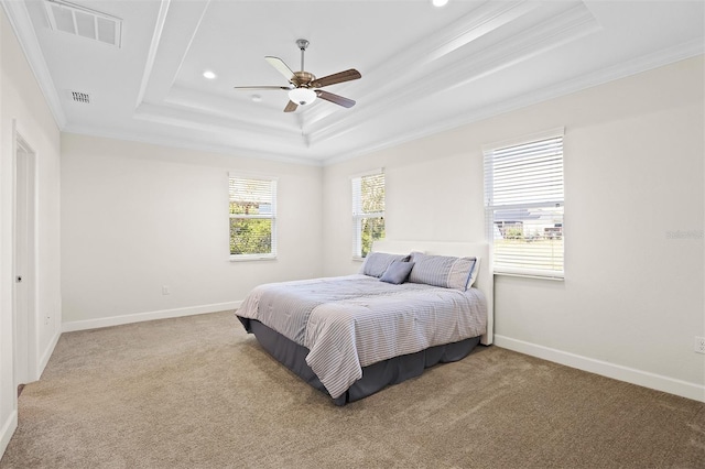 carpeted bedroom with ceiling fan, ornamental molding, and a tray ceiling