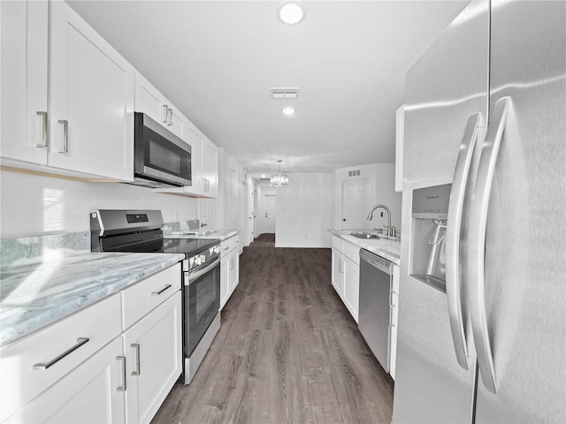 kitchen with sink, hardwood / wood-style flooring, light stone countertops, white cabinetry, and stainless steel appliances