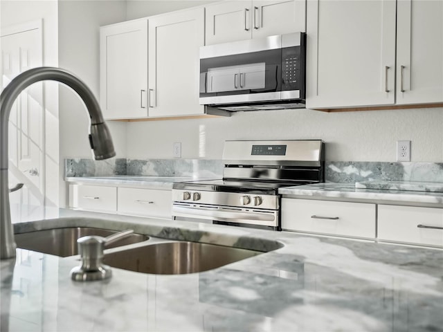 kitchen featuring light stone countertops, sink, white cabinets, and stainless steel appliances