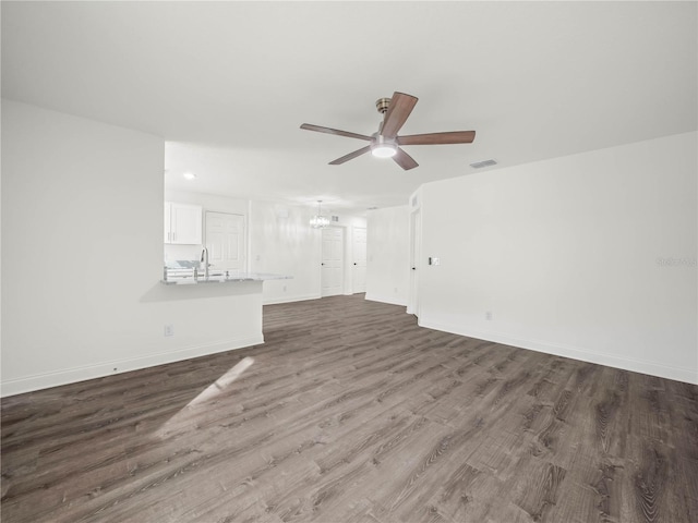 unfurnished living room with sink, dark wood-type flooring, and a chandelier