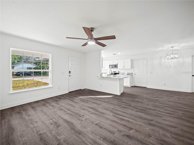 unfurnished living room featuring dark hardwood / wood-style floors, sink, and ceiling fan with notable chandelier