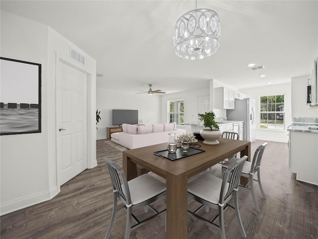 dining space featuring dark hardwood / wood-style floors, ceiling fan with notable chandelier, and a wealth of natural light