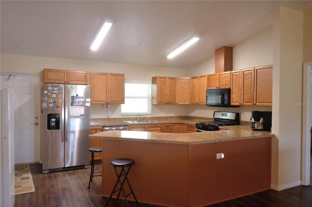 kitchen featuring sink, dark hardwood / wood-style flooring, lofted ceiling, a kitchen bar, and appliances with stainless steel finishes