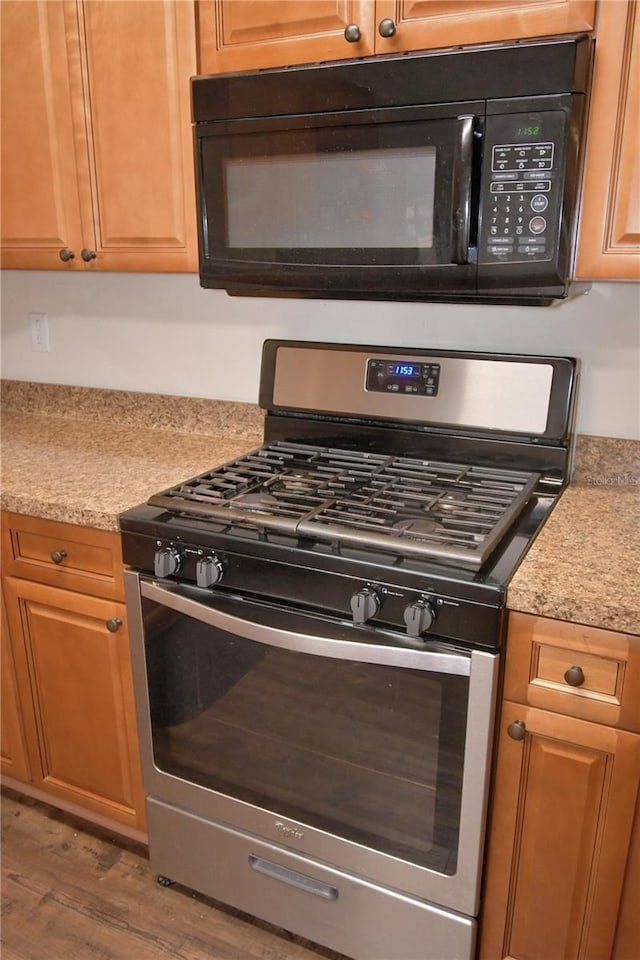 kitchen featuring gas stove, light stone counters, and hardwood / wood-style flooring