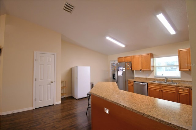 kitchen with a kitchen bar, appliances with stainless steel finishes, vaulted ceiling, sink, and dark hardwood / wood-style floors