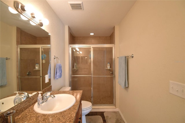 bathroom with vanity, toilet, and a shower with shower door