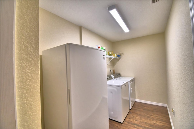 clothes washing area with washer and clothes dryer and dark wood-type flooring