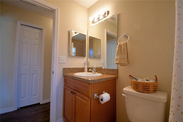 bathroom featuring vanity, wood-type flooring, and toilet