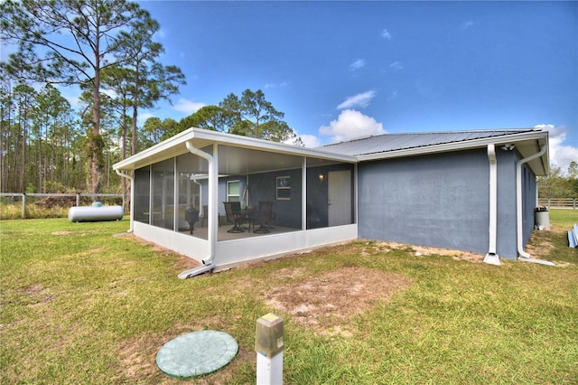 back of property featuring a sunroom and a lawn