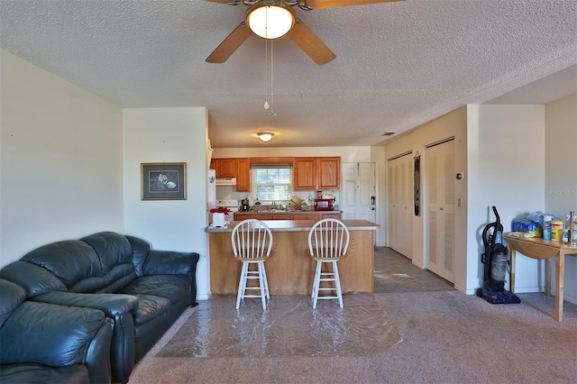 kitchen featuring a textured ceiling, a kitchen breakfast bar, kitchen peninsula, and ceiling fan