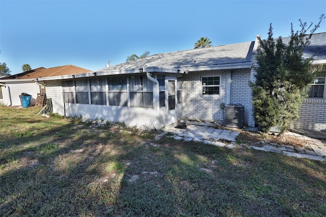 back of house featuring a yard, a sunroom, and central air condition unit