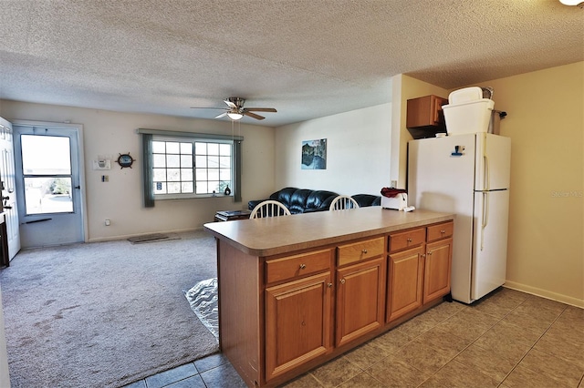 kitchen with ceiling fan, kitchen peninsula, white fridge, and a textured ceiling