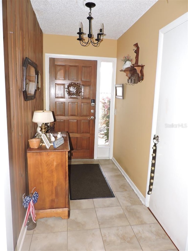 tiled entryway featuring a notable chandelier and a textured ceiling