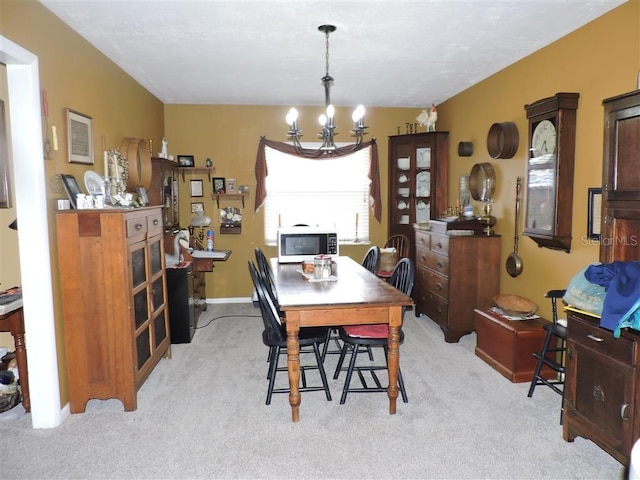 dining space featuring light carpet and a notable chandelier