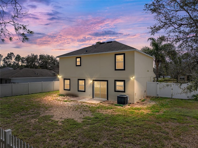 back house at dusk featuring a yard, a patio area, and cooling unit