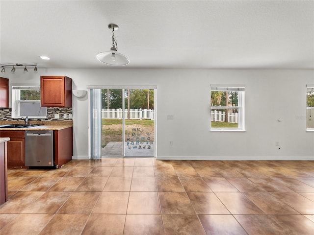 kitchen featuring hanging light fixtures, stainless steel dishwasher, decorative backsplash, light tile patterned floors, and sink