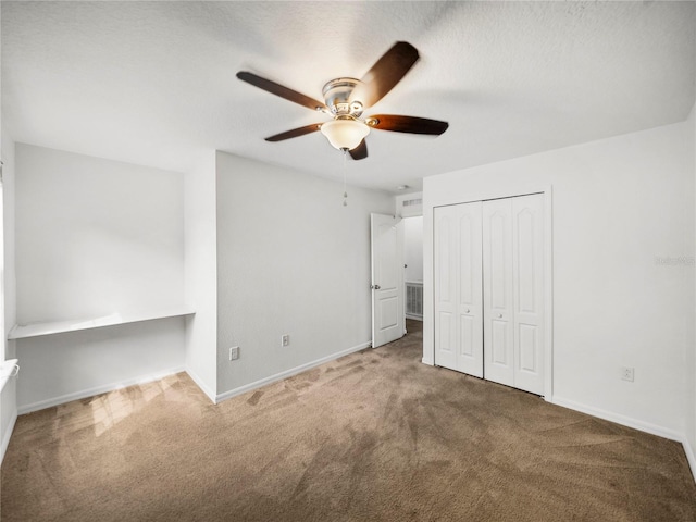 unfurnished bedroom featuring a textured ceiling, a closet, carpet flooring, and ceiling fan