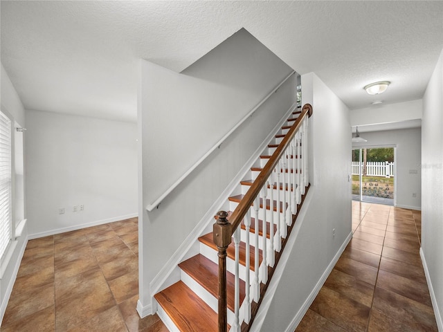 stairs featuring a textured ceiling