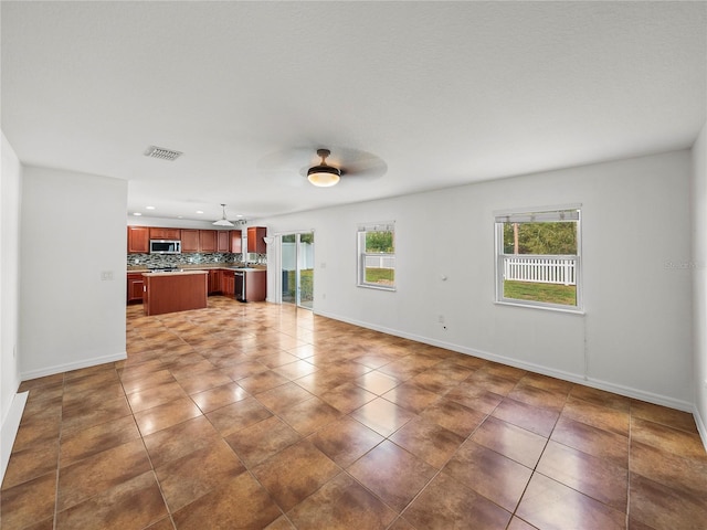 unfurnished living room with ceiling fan and dark tile patterned floors