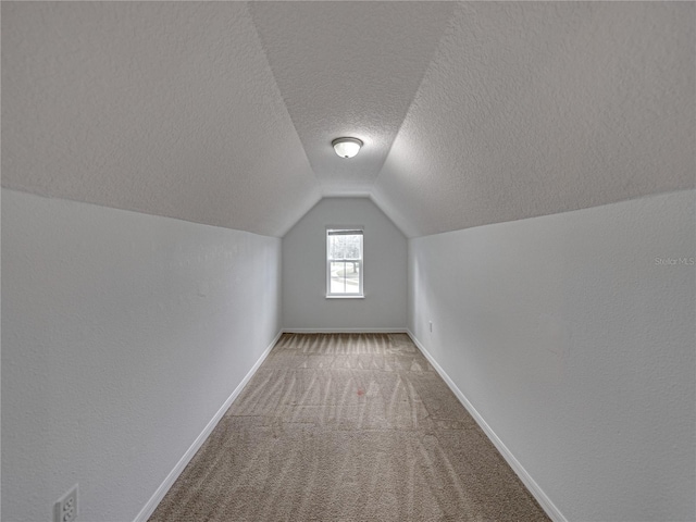 additional living space featuring carpet flooring, vaulted ceiling, and a textured ceiling