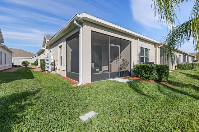 rear view of property with a lawn and a sunroom