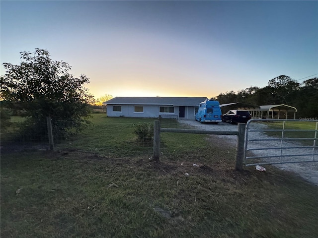 ranch-style home featuring a carport and a lawn