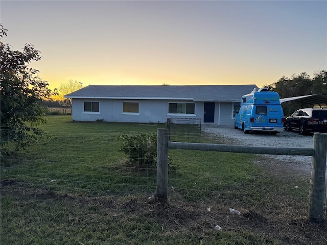 ranch-style home featuring a carport and a yard