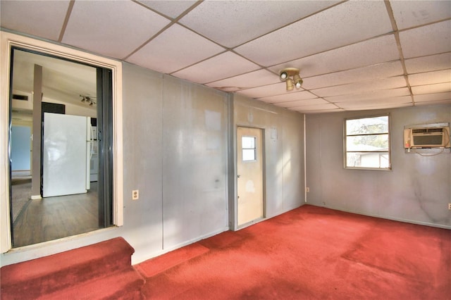 interior space featuring a paneled ceiling, carpet flooring, and a wall mounted air conditioner