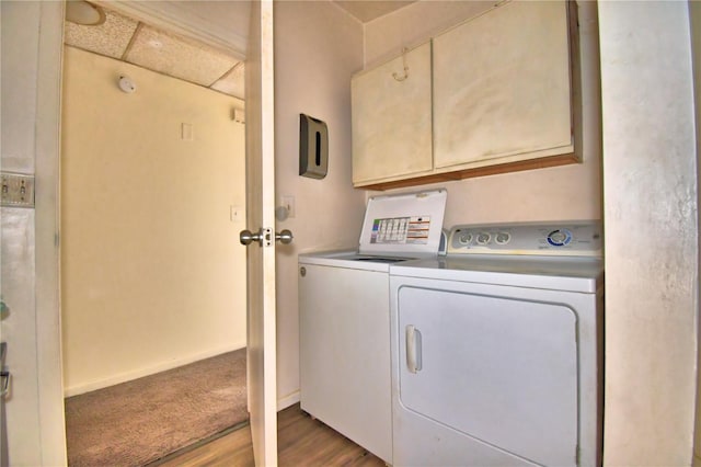 clothes washing area featuring cabinets, light hardwood / wood-style floors, and washing machine and clothes dryer