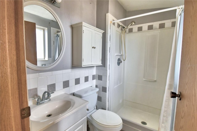 bathroom featuring lofted ceiling, vanity, tile walls, toilet, and walk in shower