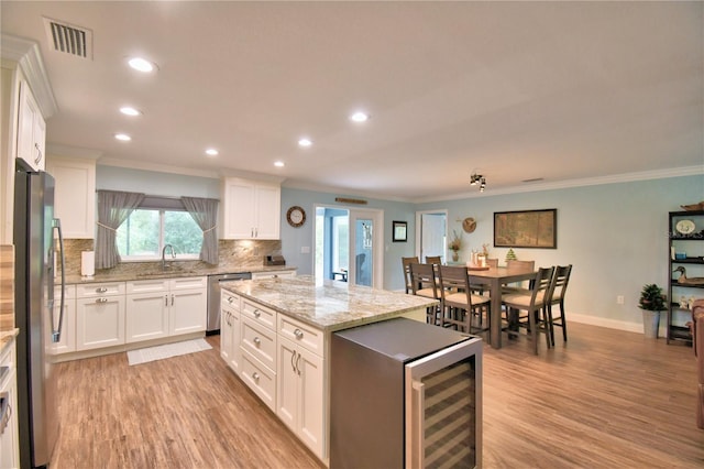 kitchen with stainless steel appliances, white cabinets, visible vents, and decorative backsplash