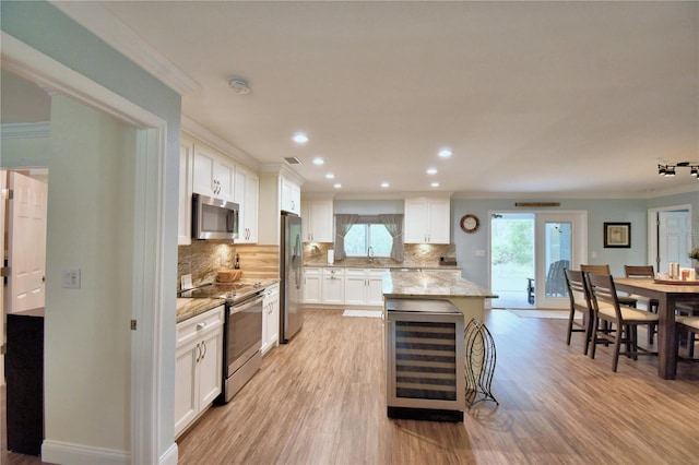 kitchen with wine cooler, light stone countertops, stainless steel appliances, white cabinets, and a center island