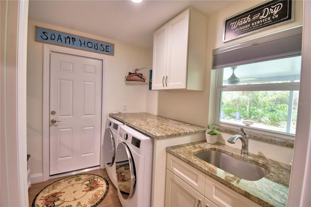 laundry area featuring cabinet space, a sink, and separate washer and dryer