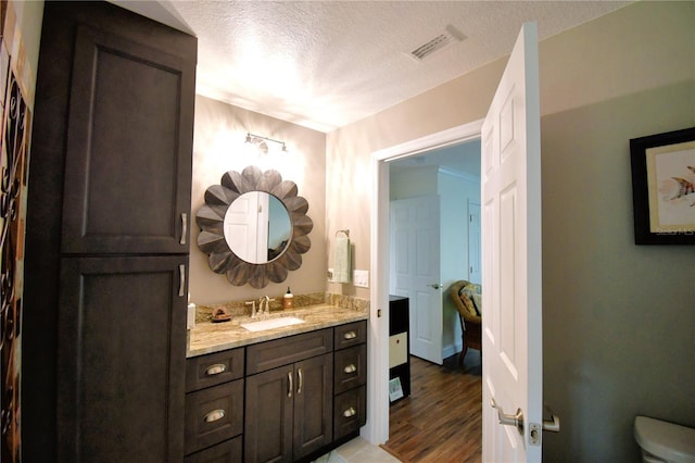 bathroom featuring toilet, a textured ceiling, vanity, and visible vents