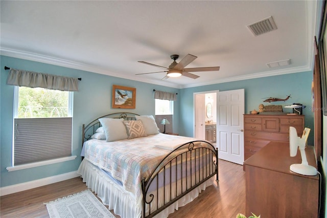 bedroom with wood finished floors, visible vents, crown molding, and multiple windows