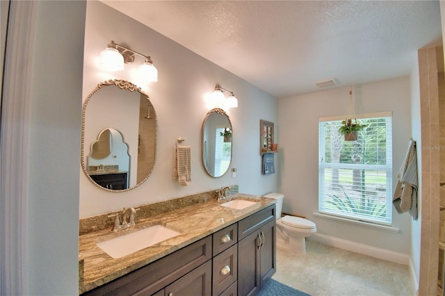 bathroom featuring toilet, double vanity, a sink, and visible vents