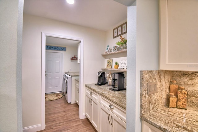 bar with independent washer and dryer and light wood-type flooring