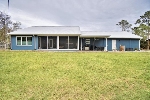 back of property with metal roof, a yard, central AC unit, and a sunroom