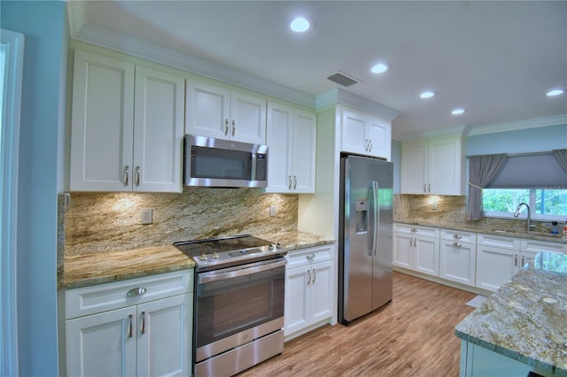 112 Reedy Creek Dr, Frostproof, FL 33843 - kitchen featuring appliances with stainless steel finishes, white cabinets, crown molding, recessed lighting, and light stone counters