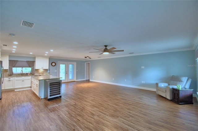 112 Reedy Creek Dr, Frostproof, FL 33843 - kitchen featuring beverage cooler, open floor plan, ornamental molding, light countertops, and white cabinets