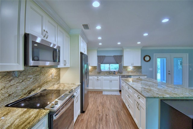 112 Reedy Creek Dr, Frostproof, FL 33843 - kitchen featuring appliances with stainless steel finishes, crown molding, light stone counters, white cabinets, and recessed lighting