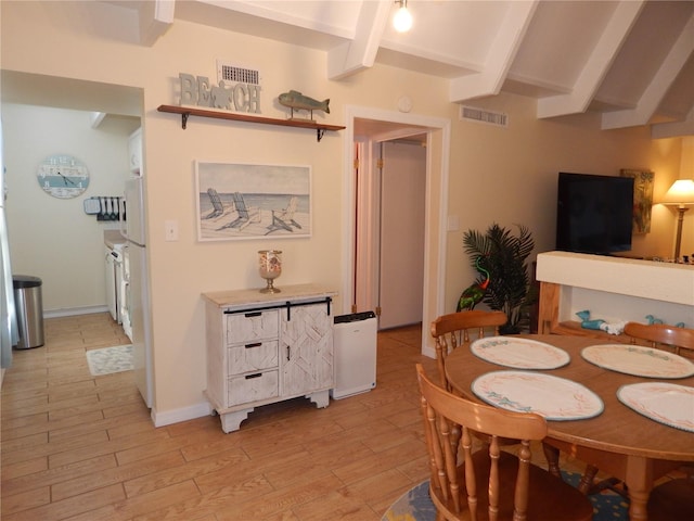 dining area featuring beam ceiling and light hardwood / wood-style flooring